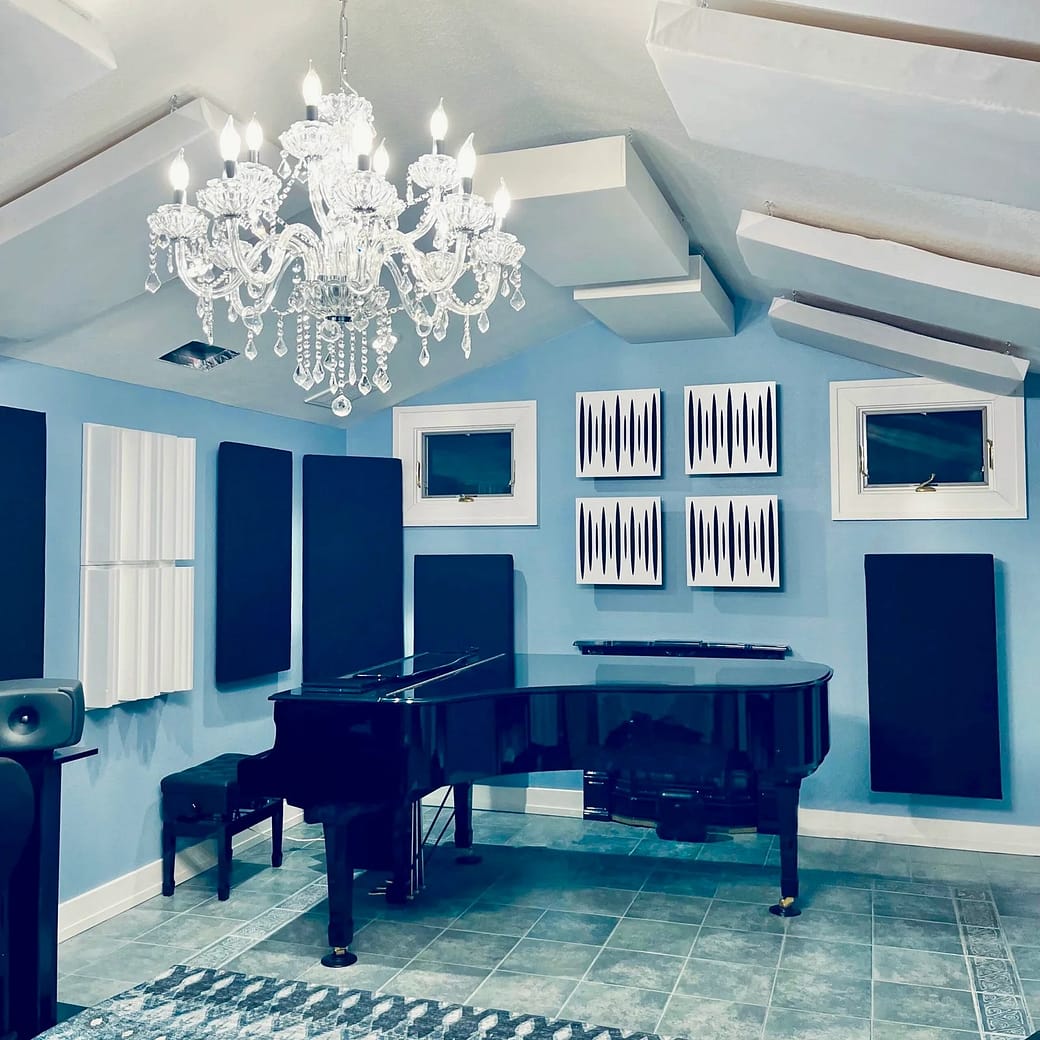 IMG_6345 Silver Moon Sound studio, a single large blue room with a grand piano and various black and white acoustic panels and acoustic diffusers on the walls and vaulted ceiling with a crystal chandelier.